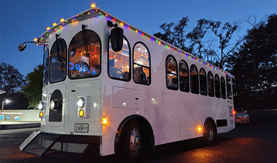 Trolley arriving at a venue entrance at dusk with string lights visible